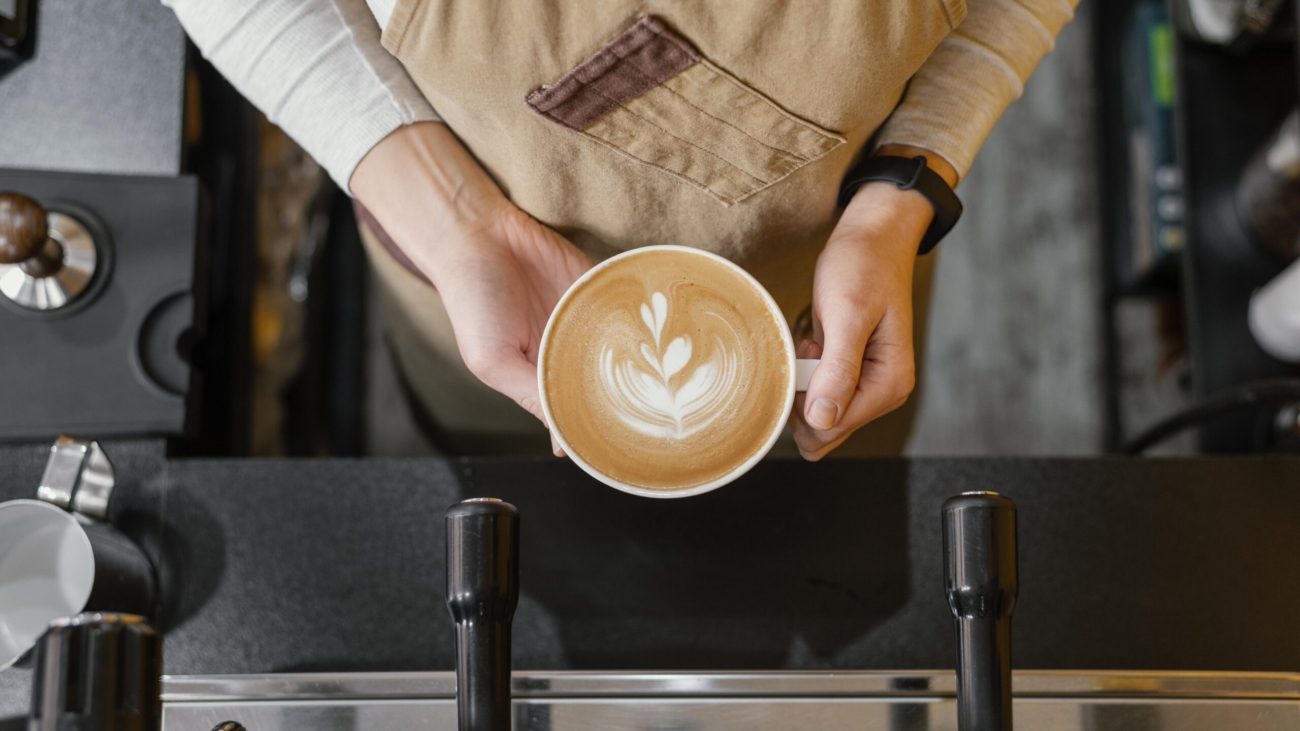 top-view-female-barista-holding-cup-coffee